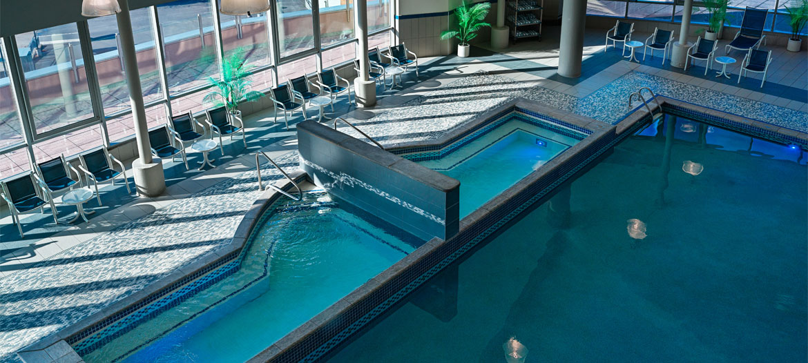 Serene indoor pool with comfortable seating and natural light streaming through large windows.
